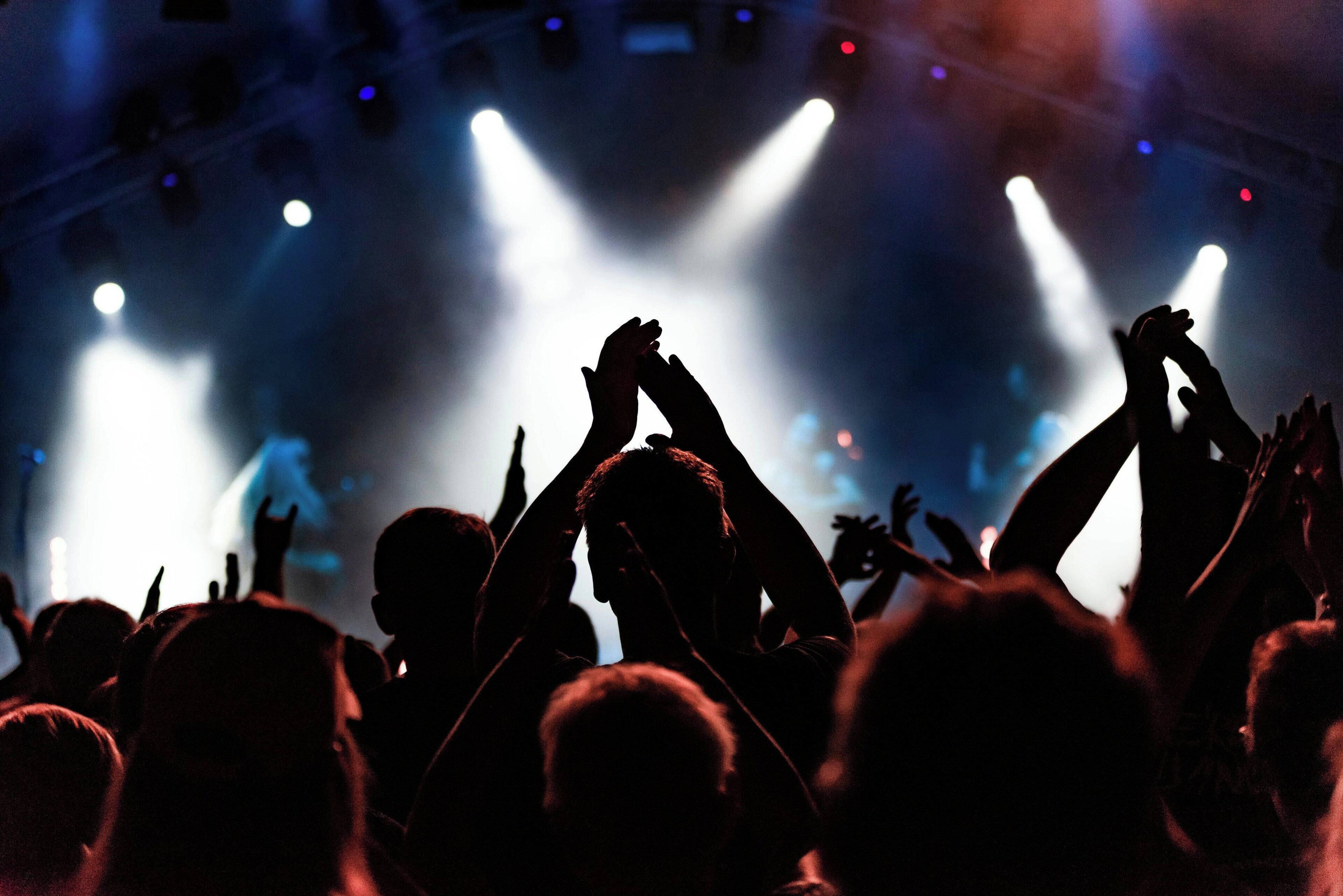 A crowd at a concert with stage lights.