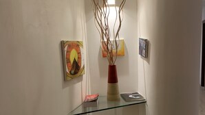 A glass display shelf with a vase and books, surrounded by white walls and artwork. - Lungotevere Collection Suite (Rome)