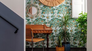 A hallway with a wooden bench, a round woven mirror, and two potted plants. - Balate Dimora In Centro (Ragusa)