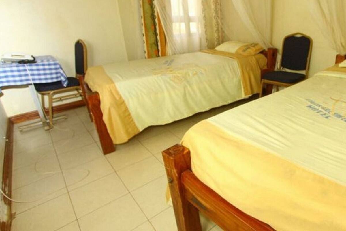 A hotel room with two single beds, a desk with a chair, and a telephone.
