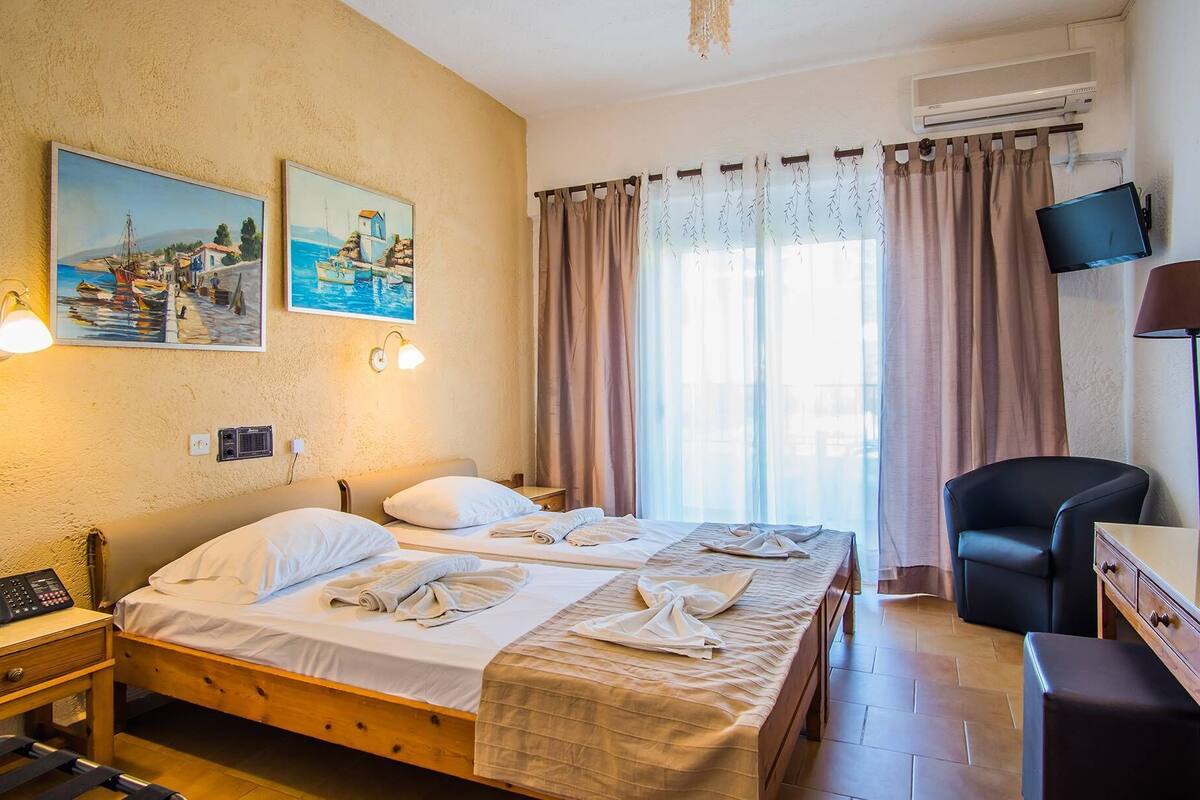 Een hotelkamer met twee bedden, een bureau, een stoel, een televisie en kunst aan de muur.