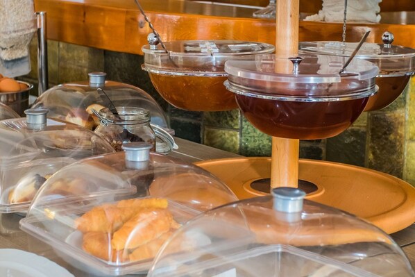 Un buffet avec des plats présentés dans des récipients couverts et une zone centrale pour se servir.