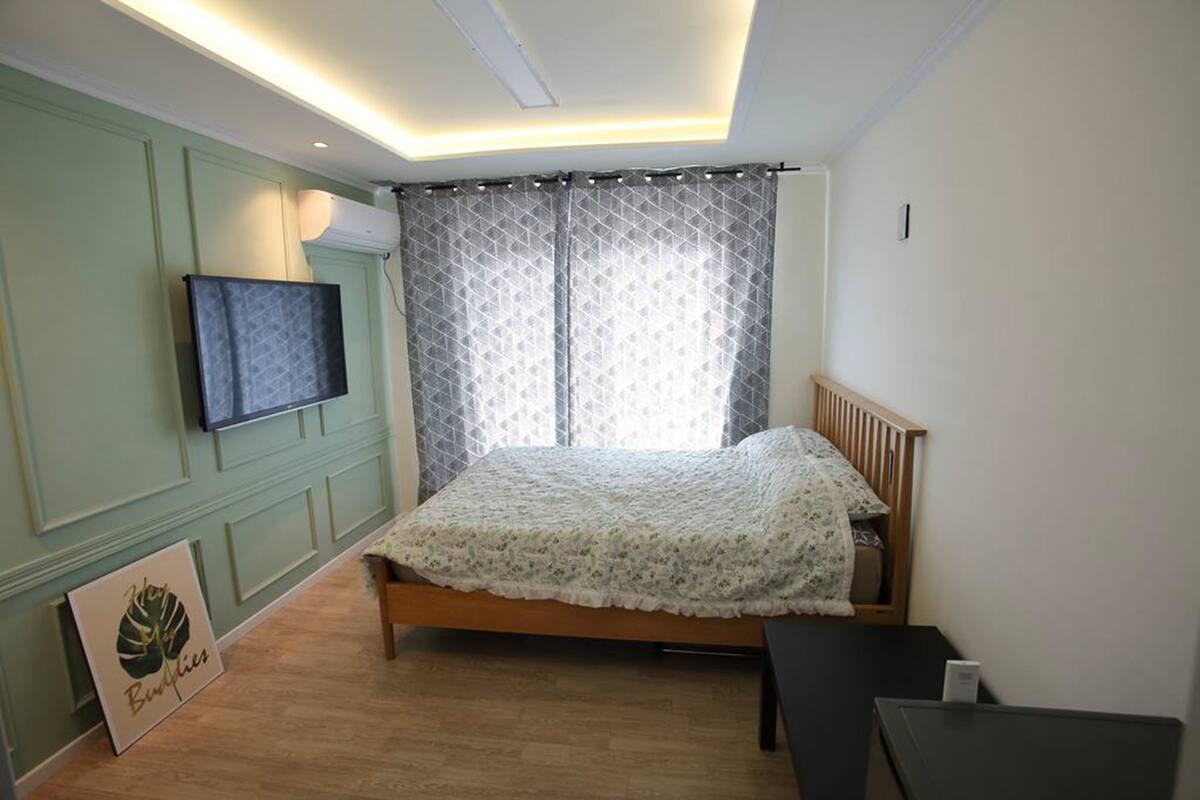 A bedroom with a bed, a TV mounted on the wall, and a bedside table.