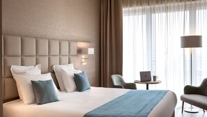 Habitación de hotel con una cama grande, cabecera con iluminación integrada, un escritorio con una computadora portátil y una silla.