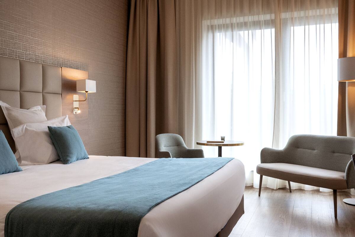 Una habitación de hotel con una cama grande, un sofá, una silla y una mesita.