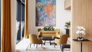 Un vestíbulo moderno con un gran cuadro abstracto, una araña y una zona de estar con una mesa de centro.