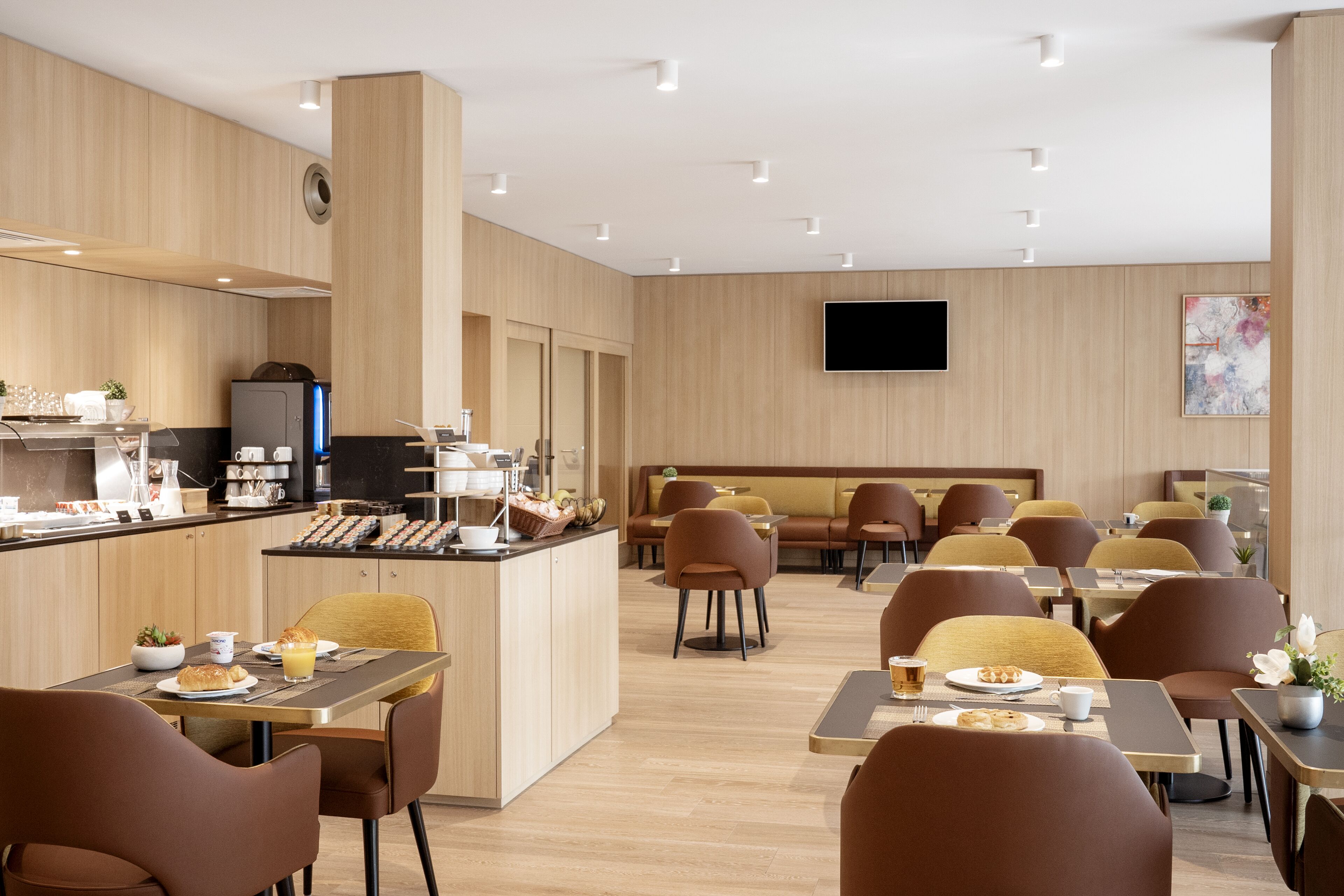 A modern restaurant with wooden paneling, a flat-screen TV, and a variety of seating options including tables and booths.