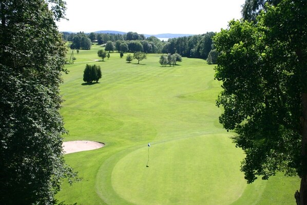 A golf course with a flagstick, sand bunkers, and trees. - Torreby Slott Hotel & Golf (Munkedal)
