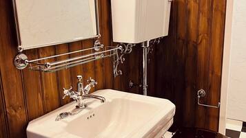 Een badkamer met een wit wastafel, houten paneelwanden, een toilet en een spiegel.