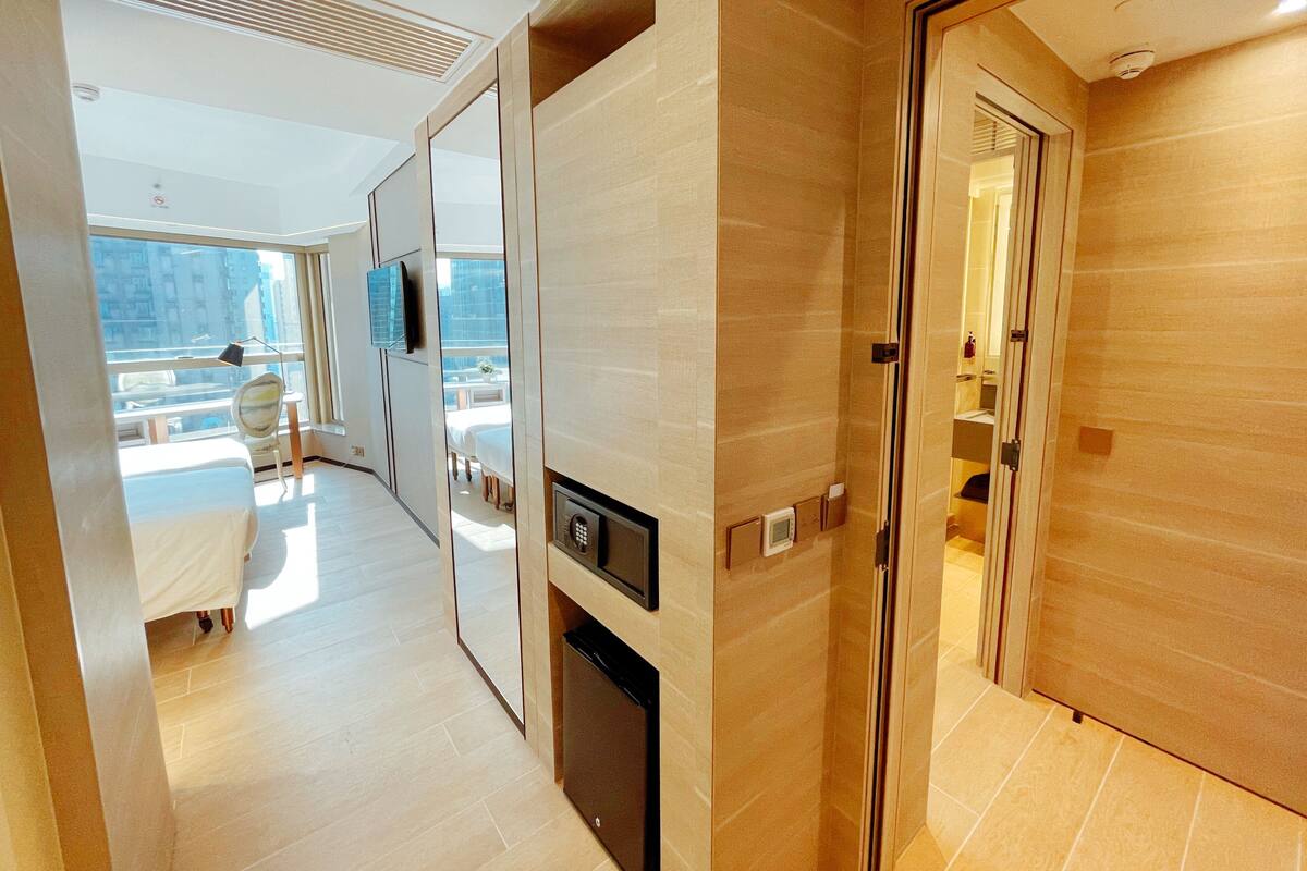 A modern hotel room with a large window, a flat-screen TV, a built-in heater, and a door leading to a balcony.