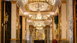 A luxurious lobby with a grand chandelier, marble columns, and a checkered floor. - Hotel Alexandra (Hong Kong)