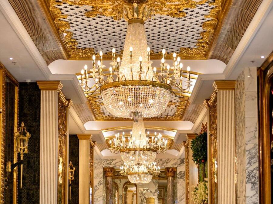 Un'elegante hall con un imponente lampadario, colonne in marmo e pavimento a scacchi.