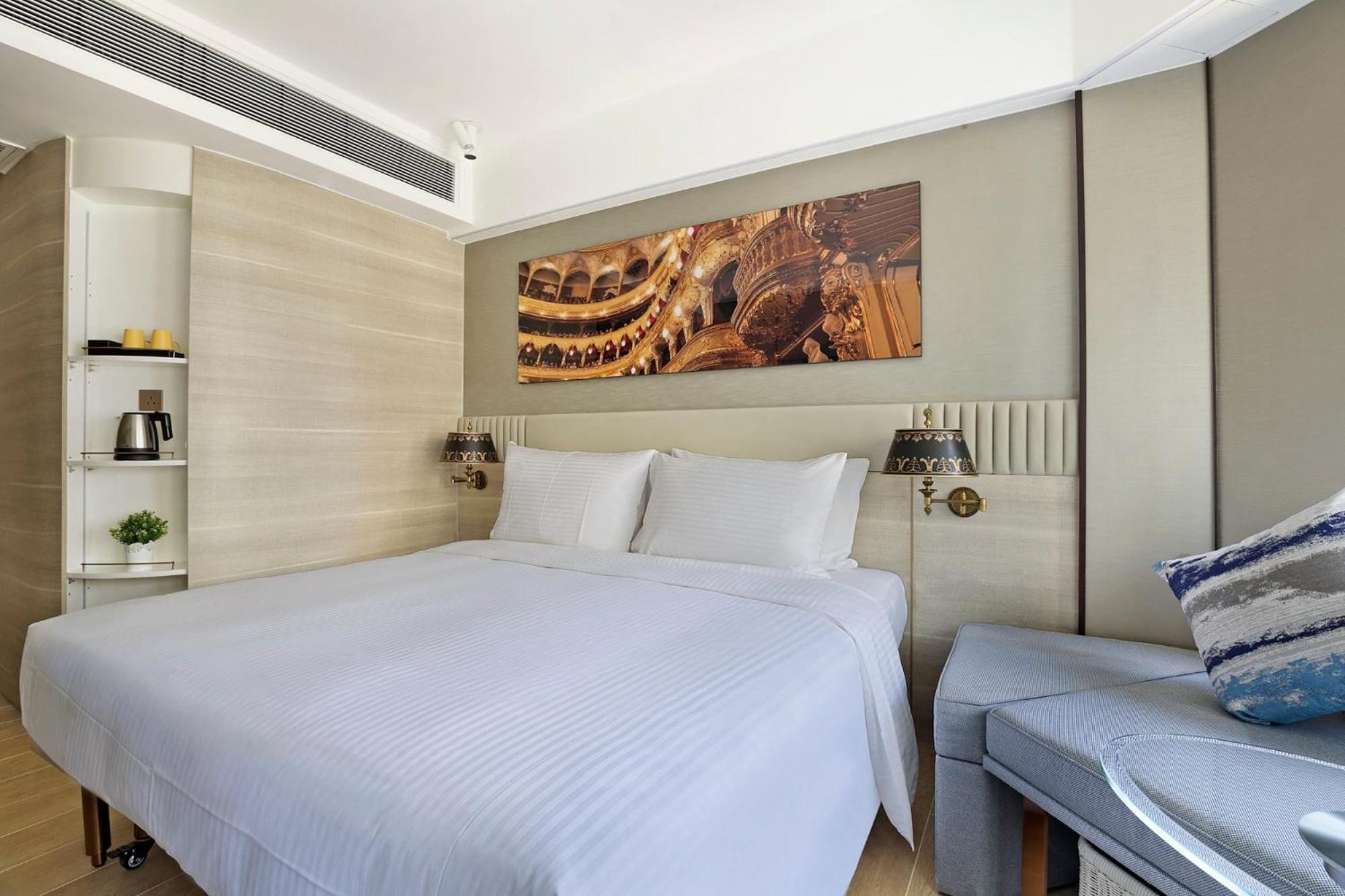Ein modernes Hotelzimmer mit einem großen Bett, Nachttischlampen, einem kleinen Tisch und einem dekorativen Wandbild.