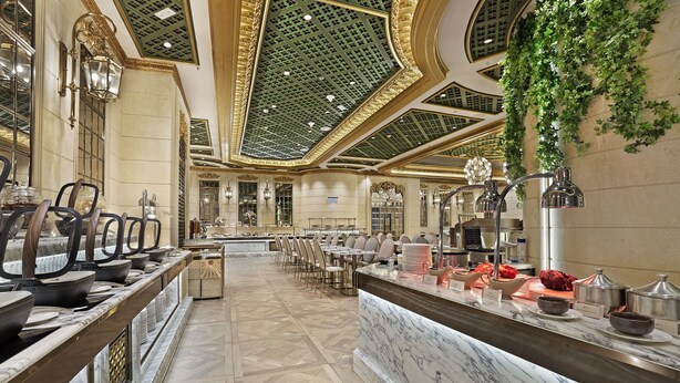 A spacious hotel lobby with marble flooring, a central reception desk, and a long dining area with tables and chairs. - Hotel Alexandra (Hong Kong)
