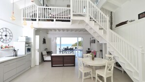 A spacious kitchen with white cabinetry, a dining area with a white table and chairs, and a white staircase leading to an upper level. - Our villa facing the Caribbean Sea (District Choiseul)