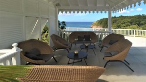 A covered outdoor seating area with wicker furniture and a view of the ocean. - Our villa facing the Caribbean Sea (District Choiseul)