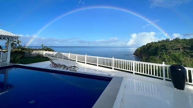 A pool area with a view of the ocean and a rainbow. - Our villa facing the Caribbean Sea (District Choiseul)