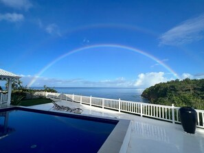 Area piscina con vista sull'oceano e un arcobaleno.