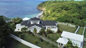 A coastal property with a large house, a white fence, and a view of the ocean. - Our villa facing the Caribbean Sea (District Choiseul)