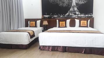 Een hotelkamer met twee bedden, een groot schilderij van de Eiffeltoren en een houten vloer.
