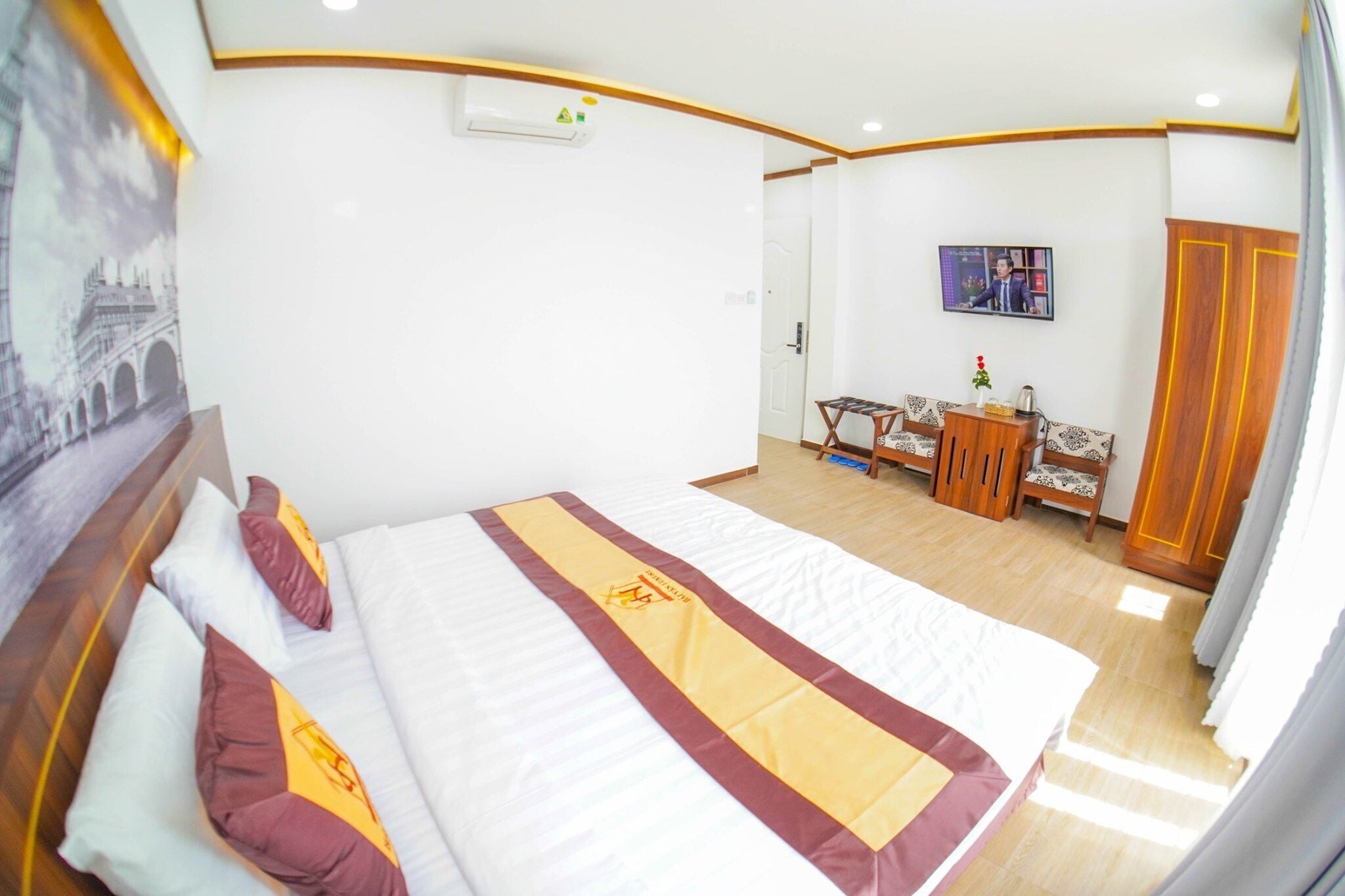 Ein Hotelzimmer mit einem großen Bett, einem Schreibtisch, einem Sessel, einem Fernseher und einem Kleiderschrank.