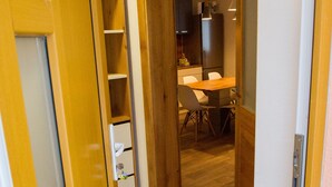 A hallway with a wooden door, a small white cabinet, and a dining area with a table and chairs. - Apartments Laznica (Cerkno)