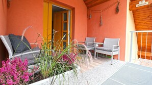 A covered outdoor seating area with wicker chairs, a table, and potted plants. - Apartments Laznica (Cerkno)