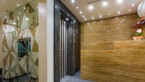A reception area with a wooden reception desk, a geometric glass partition, and a marble floor. - Hotel Imperial (Ajmer)