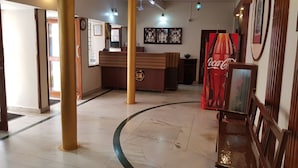 A hotel lobby with a reception desk, framed pictures on the walls, and a Coca-Cola vending machine. - Sri Kumara Lodge (Bengaluru)