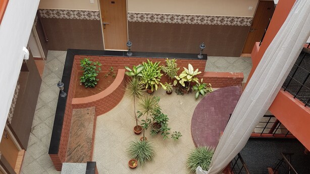 A courtyard with potted plants, a brick pathway, and a staircase. - Sri Kumara Lodge (Bengaluru)