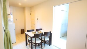 A dining area with a table, chairs, and a refrigerator. - Tenjin Higashi Russo (Fukuoka)