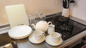 A kitchen with a stove, teapot, cups, and plates. - Tenjin Higashi Russo (Fukuoka)