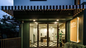 A modern building entrance with a checkered floor, a desk, and a chair inside.