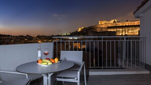 A balcony with a round table, a bottle of wine, and a fruit bowl.