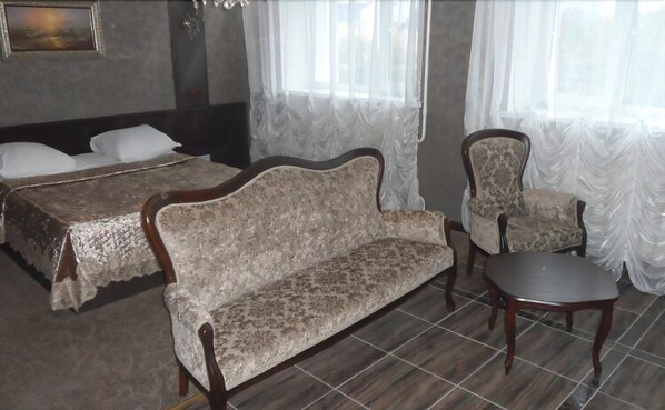 A bedroom with a bed, a sofa, a chair, and a small table. - Hotel Vetraz (Vitebsk)