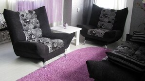 A living room with two black armchairs with floral upholstery, a white coffee table, and a purple rug. - Hotel Vetraz (Vitebsk)
