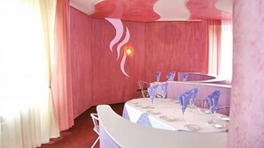 A room with a pink wall, a round table with a white tablecloth, and a mirror above the table. - Hotel Vetraz (Vitebsk)