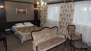 A hotel room with a bed, a sofa, a chair, a small table, and a chandelier. - Hotel Vetraz (Vitebsk)