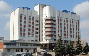 A multi-story hotel with a central atrium, a parking area, and a sign indicating a business center. - Hotel Vetraz (Vitebsk)