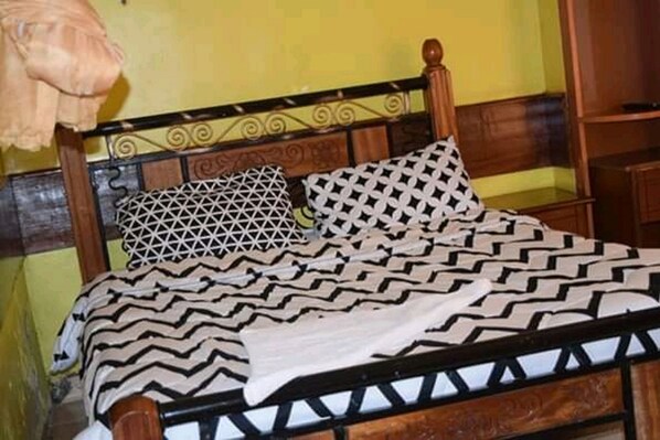 Una cama con una colcha estampada y dos almohadas geométricas.