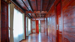 A wooden hallway with a red door at the end. - The Tetamian Bali (Sukawati)