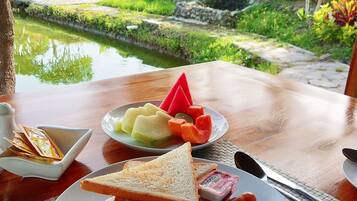 A breakfast setting with a plate of toast, sausages, tomatoes, and a small bowl of jam.