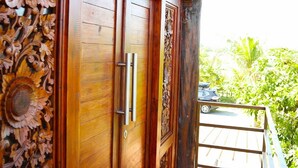 A wooden door with intricate carvings and a metal handle. - The Tetamian Bali (Sukawati)
