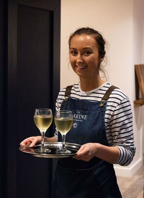 Une personne tenant un plateau sur lequel se trouvent deux verres de vin blanc.