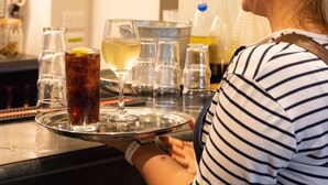 Un área de bar con una bandeja de bebidas, una copa de vino y una botella de licor.