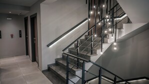 En modern trappa med ett glasräcke och inbyggd belysning, som leder upp till ett övre våningsplan.