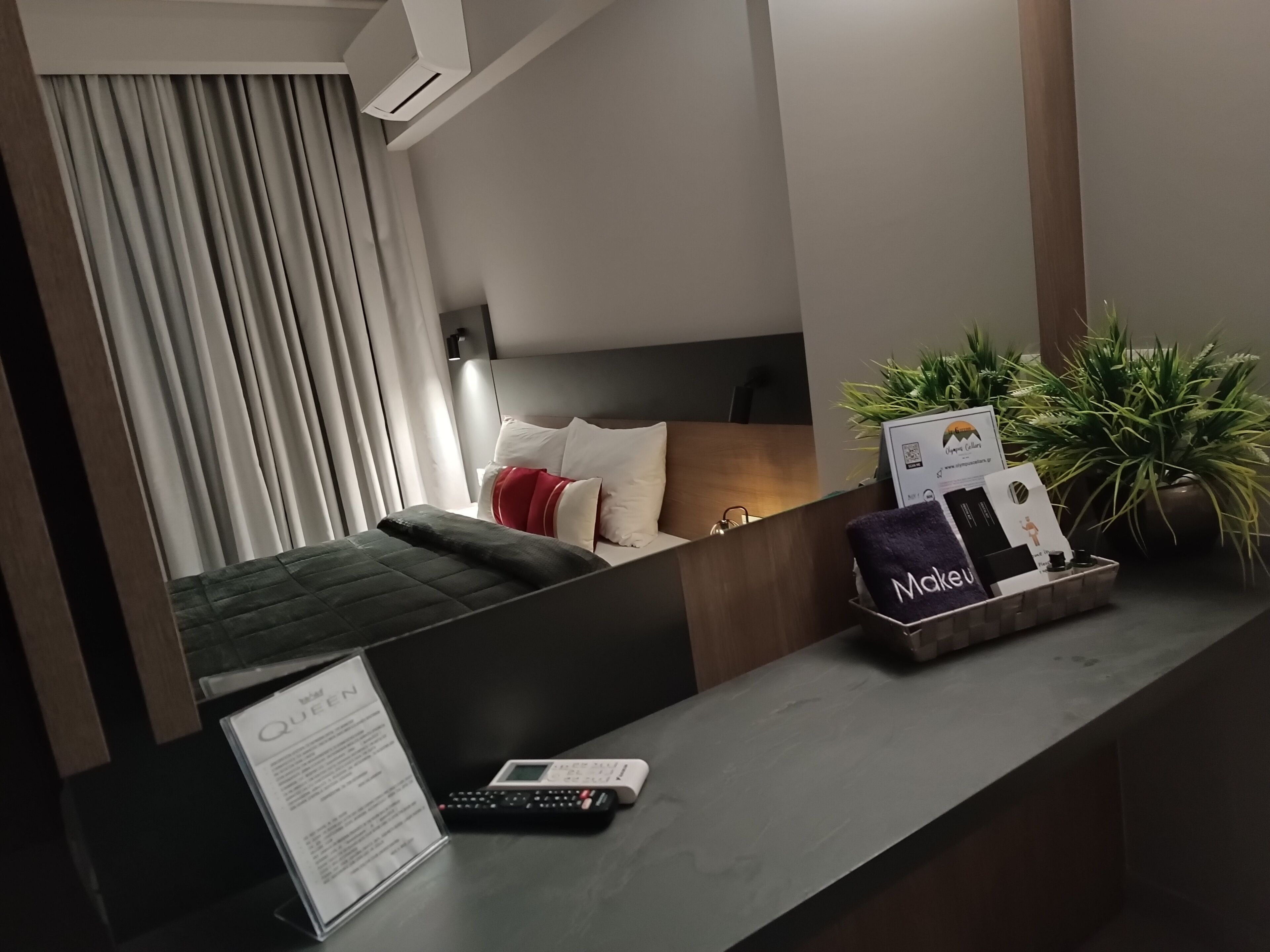 Habitación de hotel con cama, escritorio, control remoto, menú y bandeja con toalla y tarjeta.