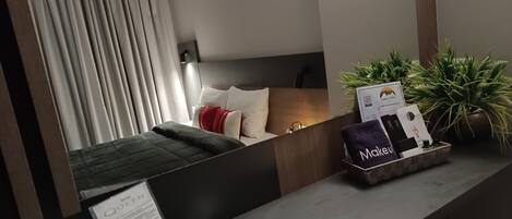 Habitación de hotel con cama, escritorio, control remoto, menú y bandeja con toalla y tarjeta.