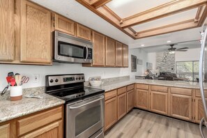 Enjoy cooking in this well-equipped kitchen with a range hood, microwave, double oven, ample cabinetry, and a durable countertop.