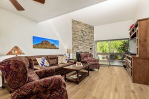 Relax in this stylish living room with a comfortable sofa, armchairs, and a coffee table, leading to a patio area with outdoor seating.